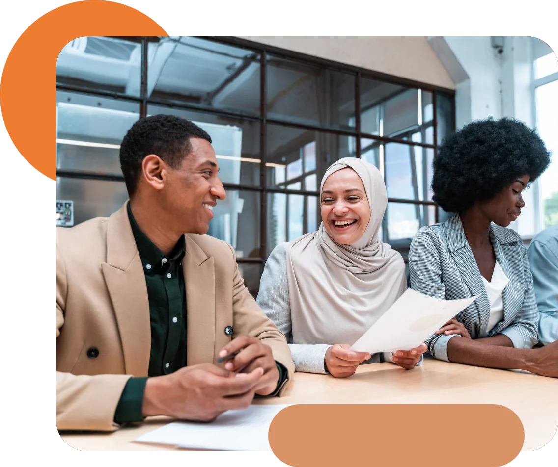 Consultants of different backgrounds smiling and discussing a document at a meeting table